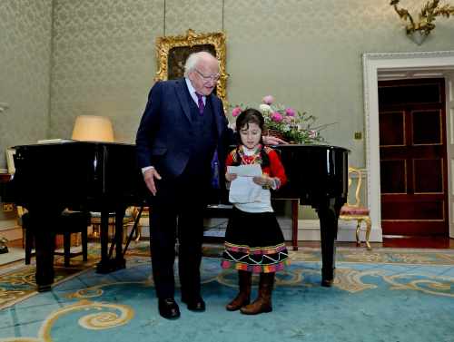 President Higgins and Saylor Burke, aged 8,  as she read a poem at a reception for members of the Peruvian Community in Ireland at Áras an Uachtaráin