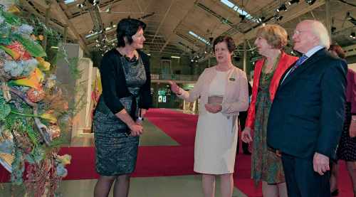 President Michael D. Higgins and Sabina Higgins being shown the Irish exhibit by Mary O'Brien, designer of the piece, and Kitty Gallagher, President of WAFA